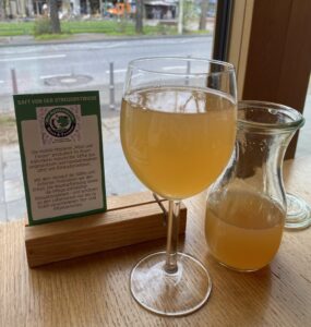 Saft in einem Glas, eine kleine Karaffe steht daneben und ein Schild mit Infos zu Most & Trester